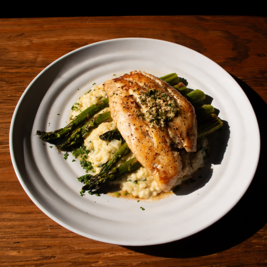 A plate of risotto topped with asparagus and pan seared grouper.
